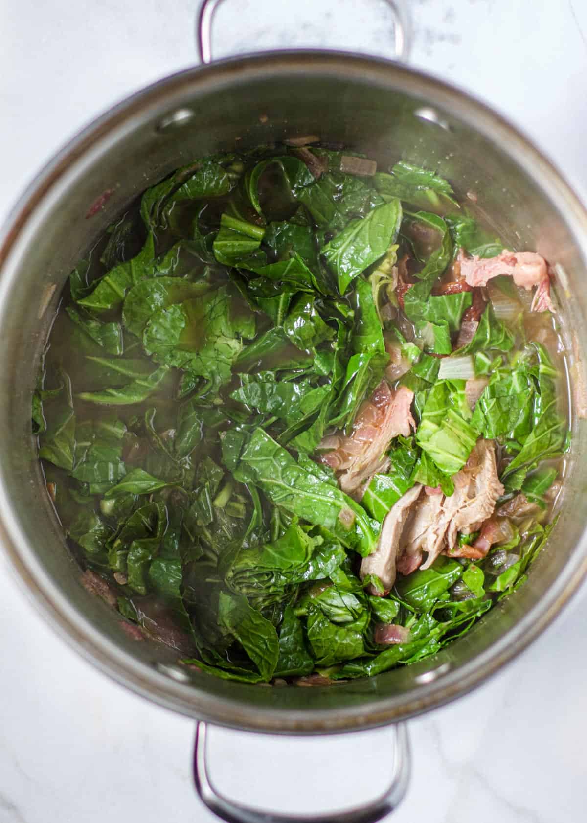 A pot of cooked collard greens with smoked turkey legs