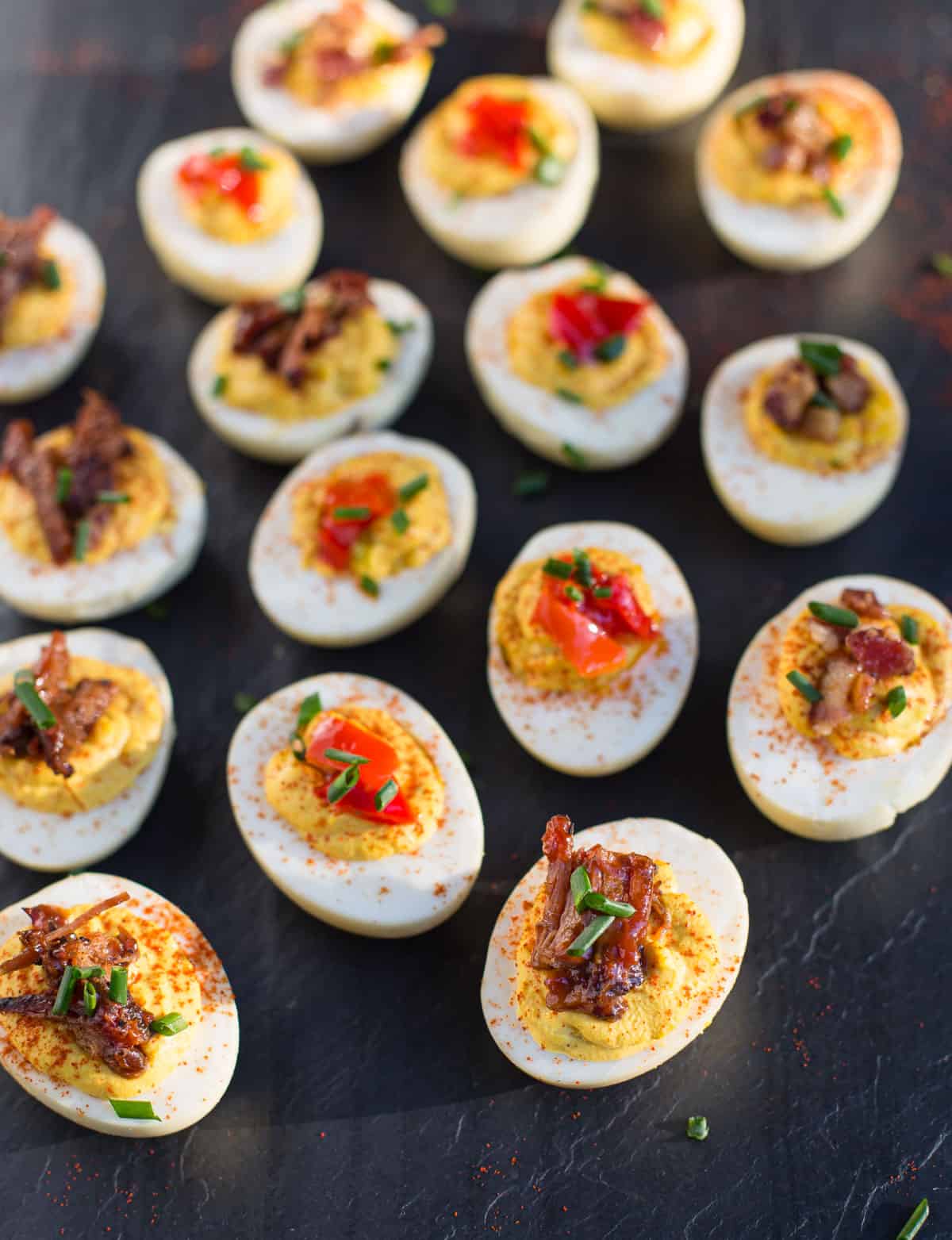 Deviled Eggs topped with brisket and Mama Lil's peppers on a slate platter