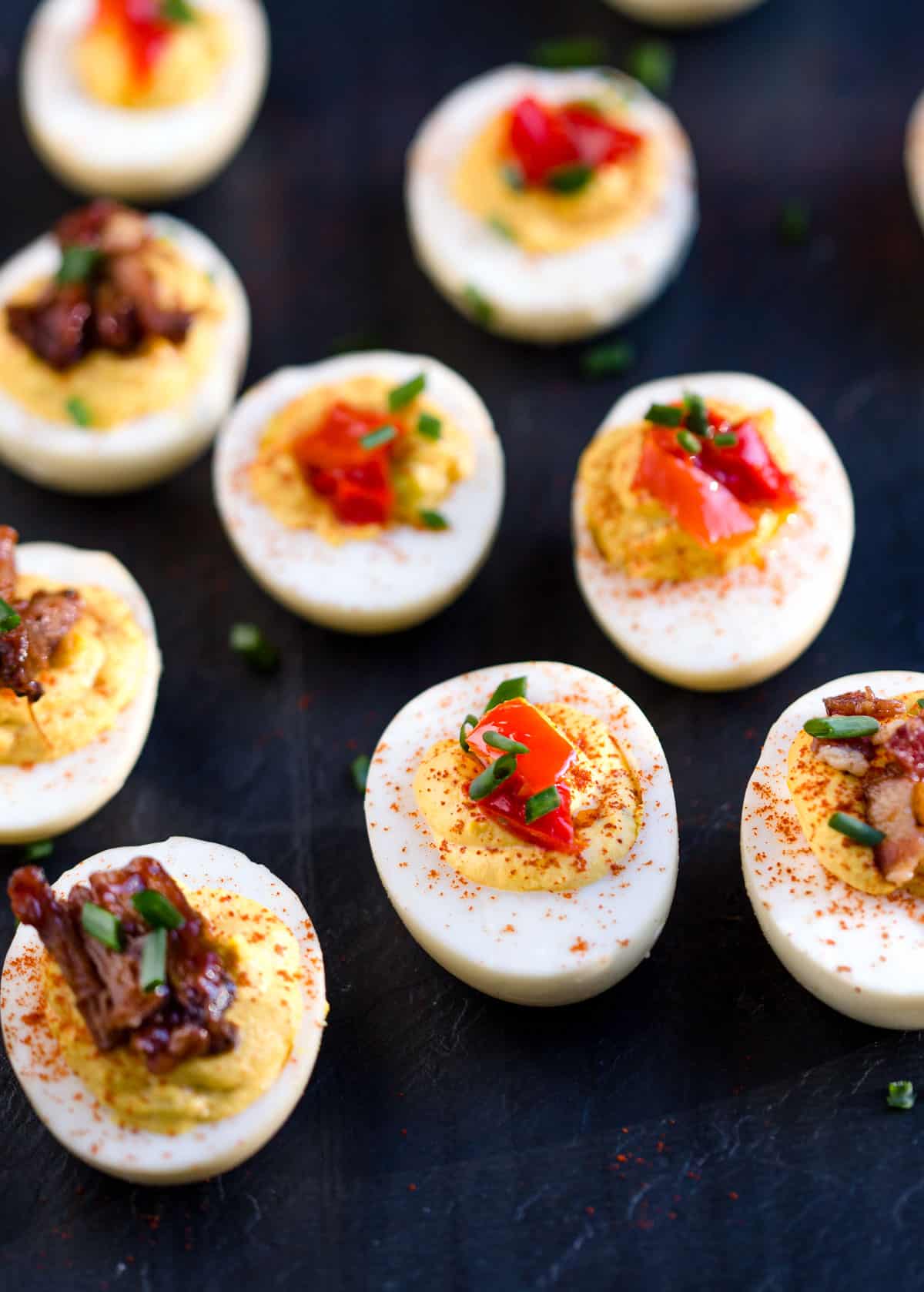 Smoked deviled eggs recipe topped with pickled hot peppers and bacon.