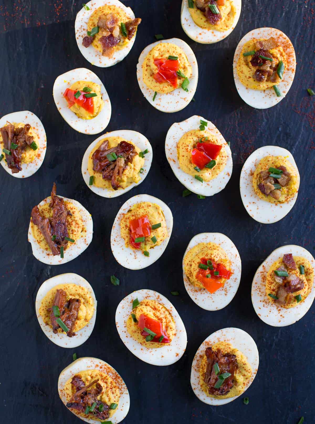 A platter full of smoked deviled eggs with mixed toppings