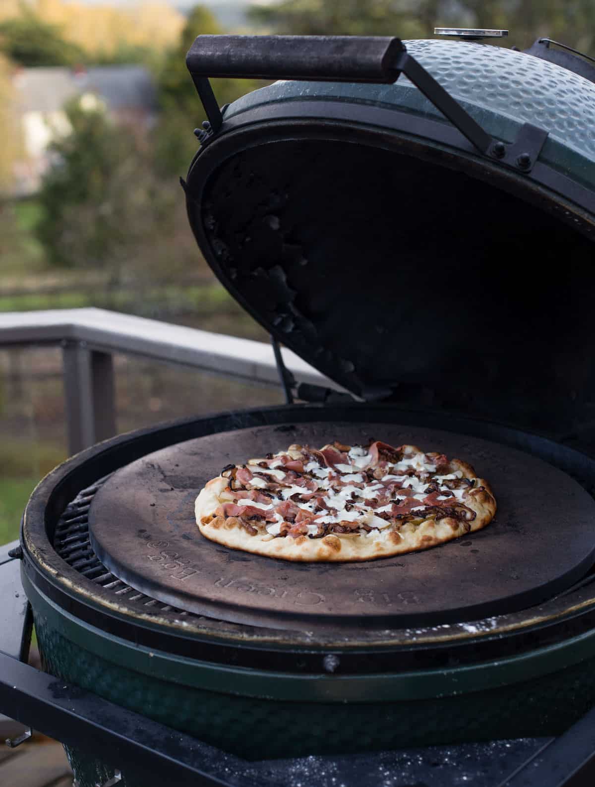 A pizza grilling on a Big Green Egg grill
