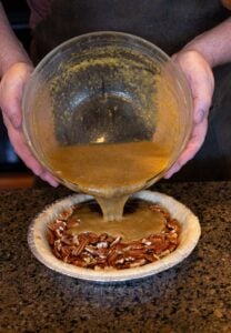 Pouring pie mix in pie.