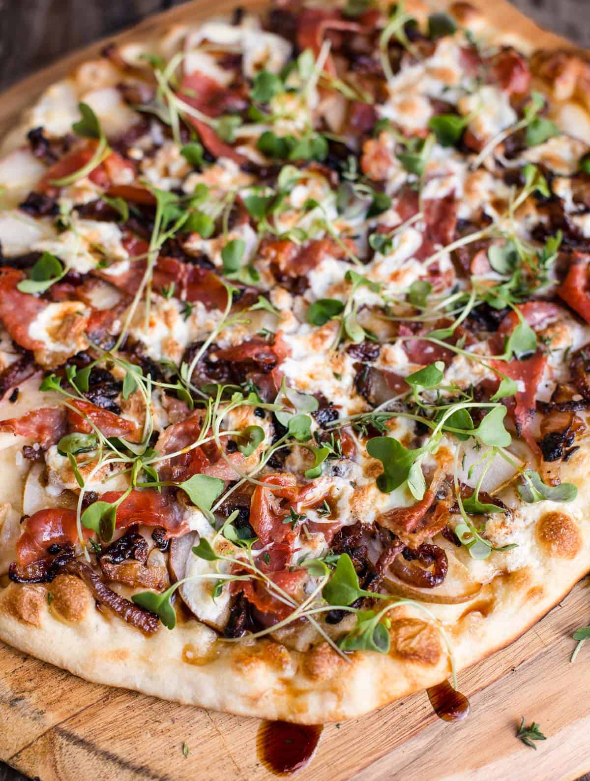 A grilled pizza with pear and prosciutto on a cutting board. 