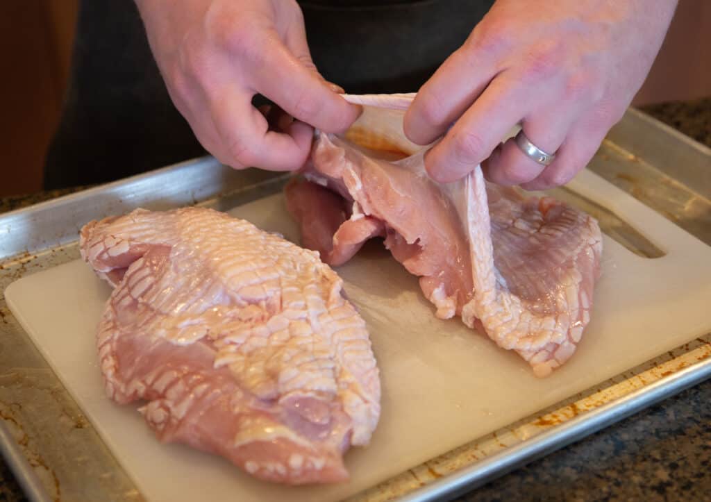 Using fingers to loosen and separate a pocket between skin and meat