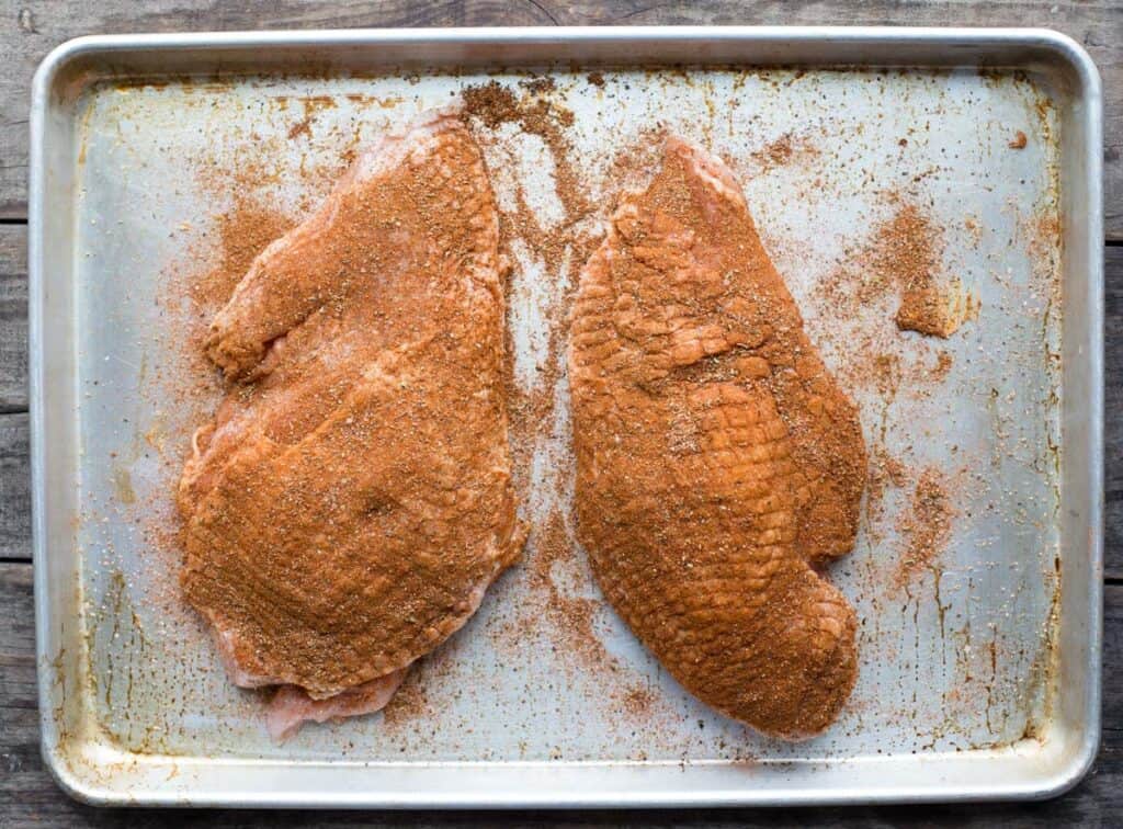 Seasoned meat on a platter prior to grilling.