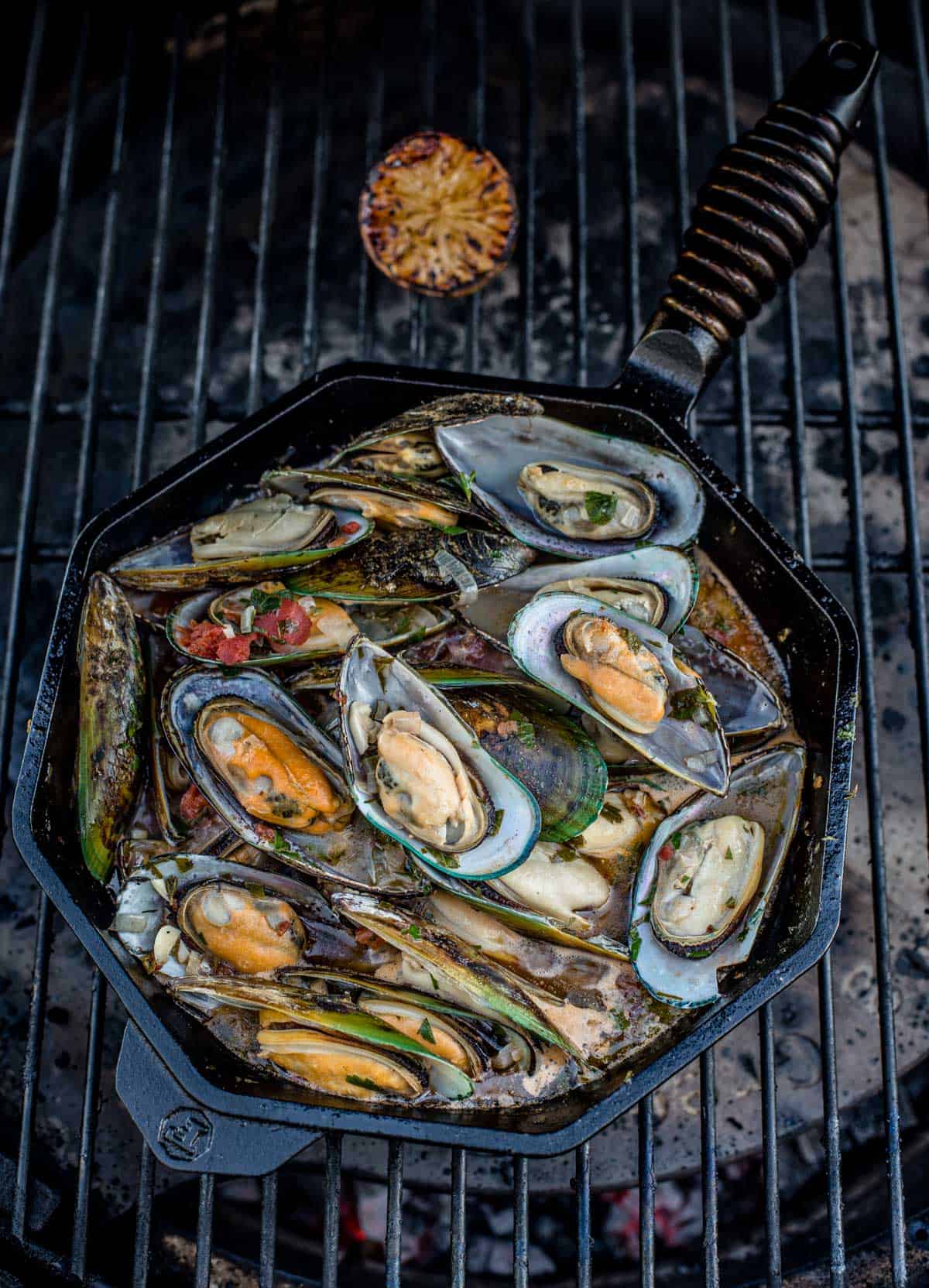Grilled mussels in a cast iron pan on a hot grill.