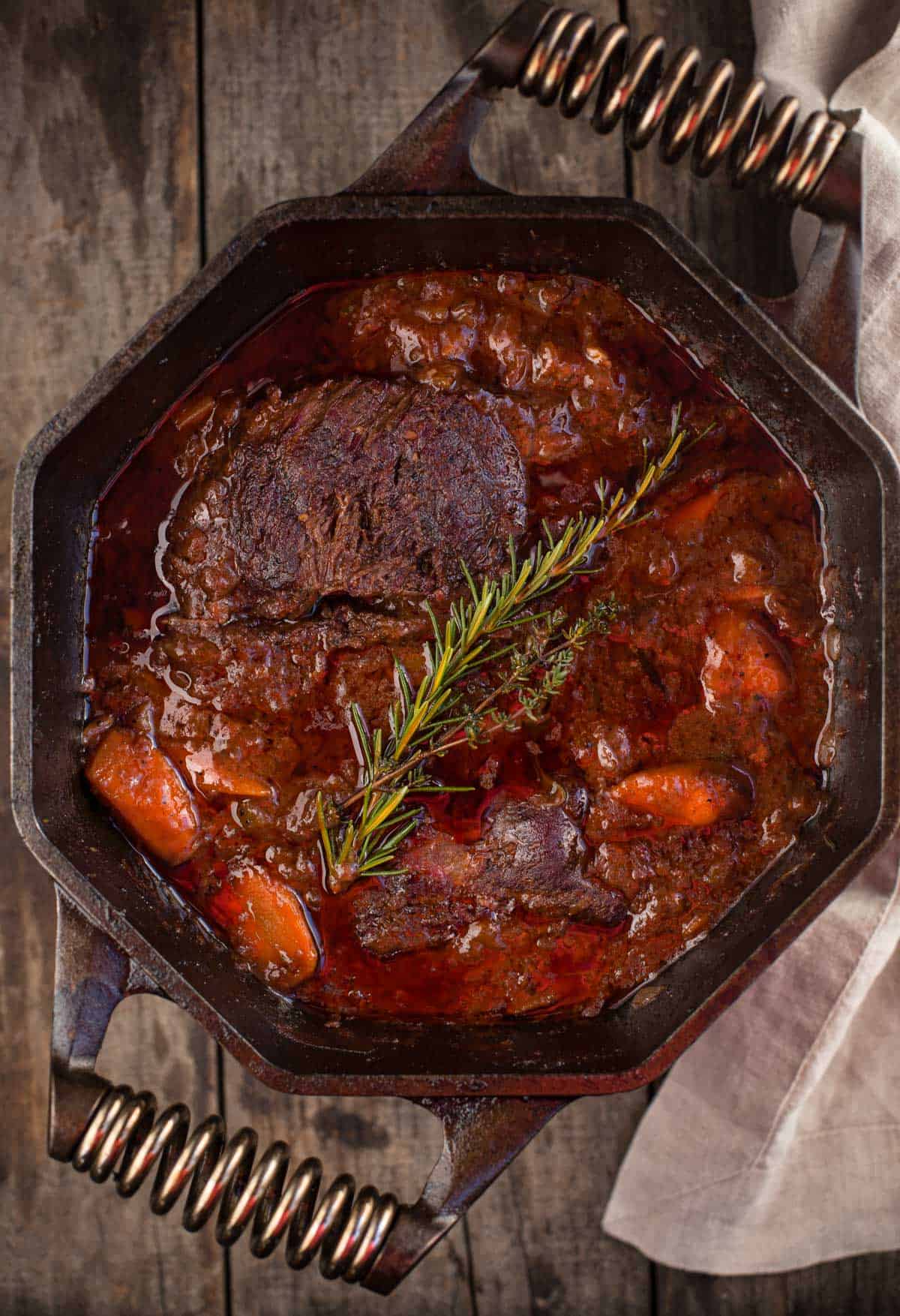 A smoked chuck roast pot roast stew in a large cast iron pan