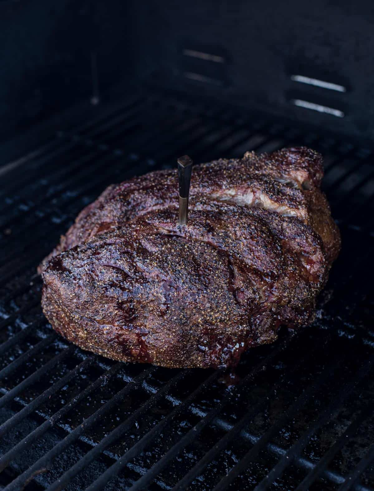 A chuck roast cooking on a smoker