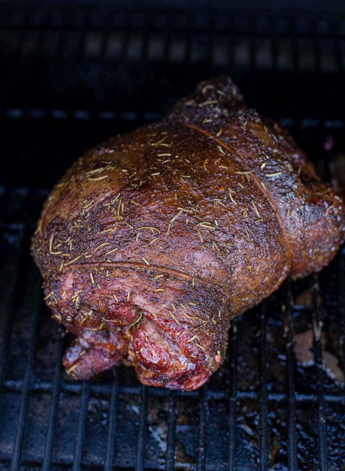 A boneless leg of lamb cooking on a smoker