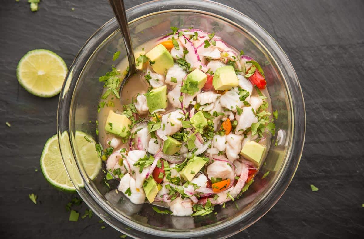 A bowl full of ceviche after adding the final ingredients of avocado and cilantro.