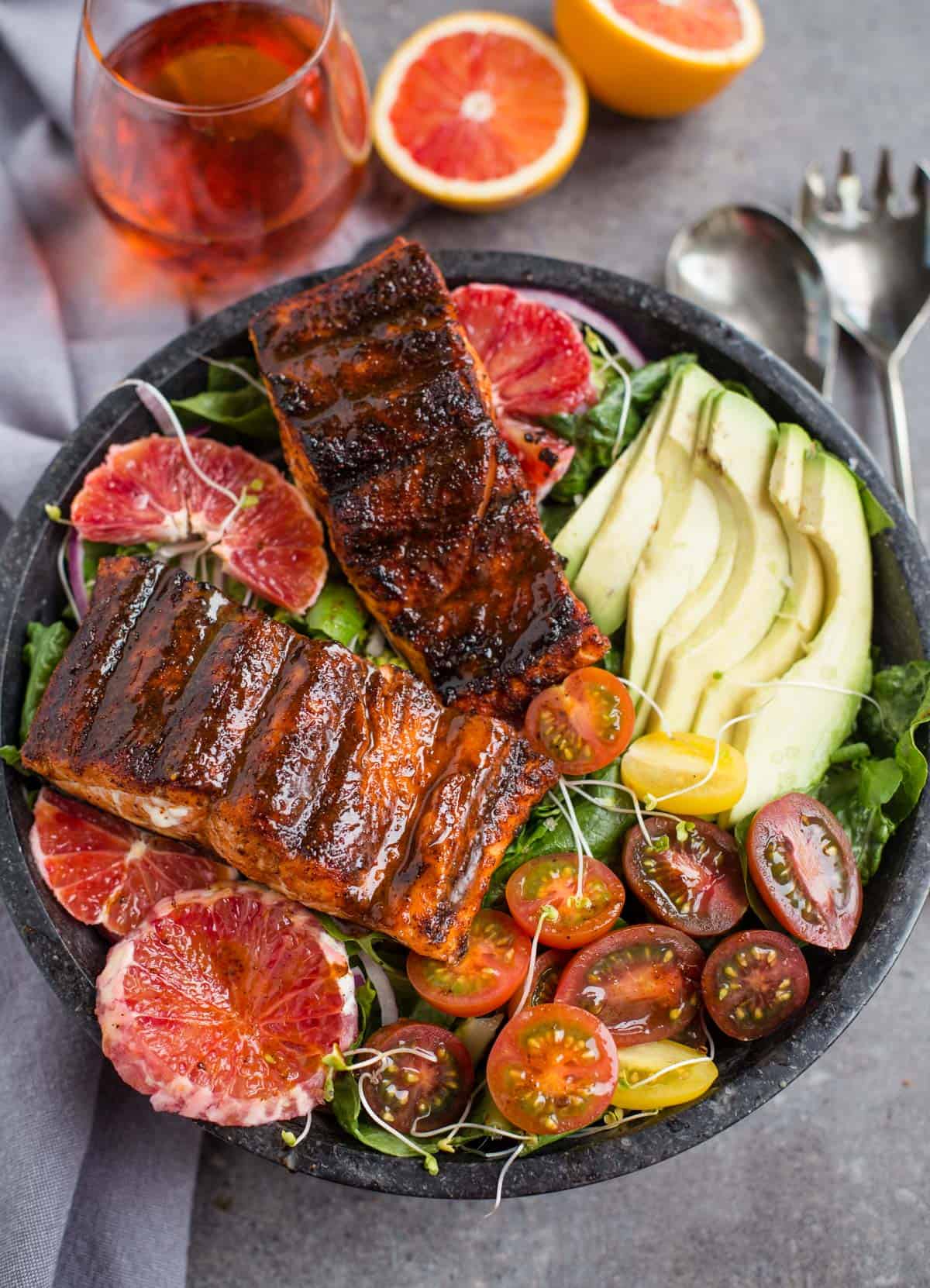 Grilled Salmon Salad in a bowl with avocado, tomatoes, and orange slices 