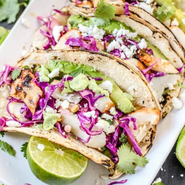 Fish Tacos on a platter with toppings and lime.