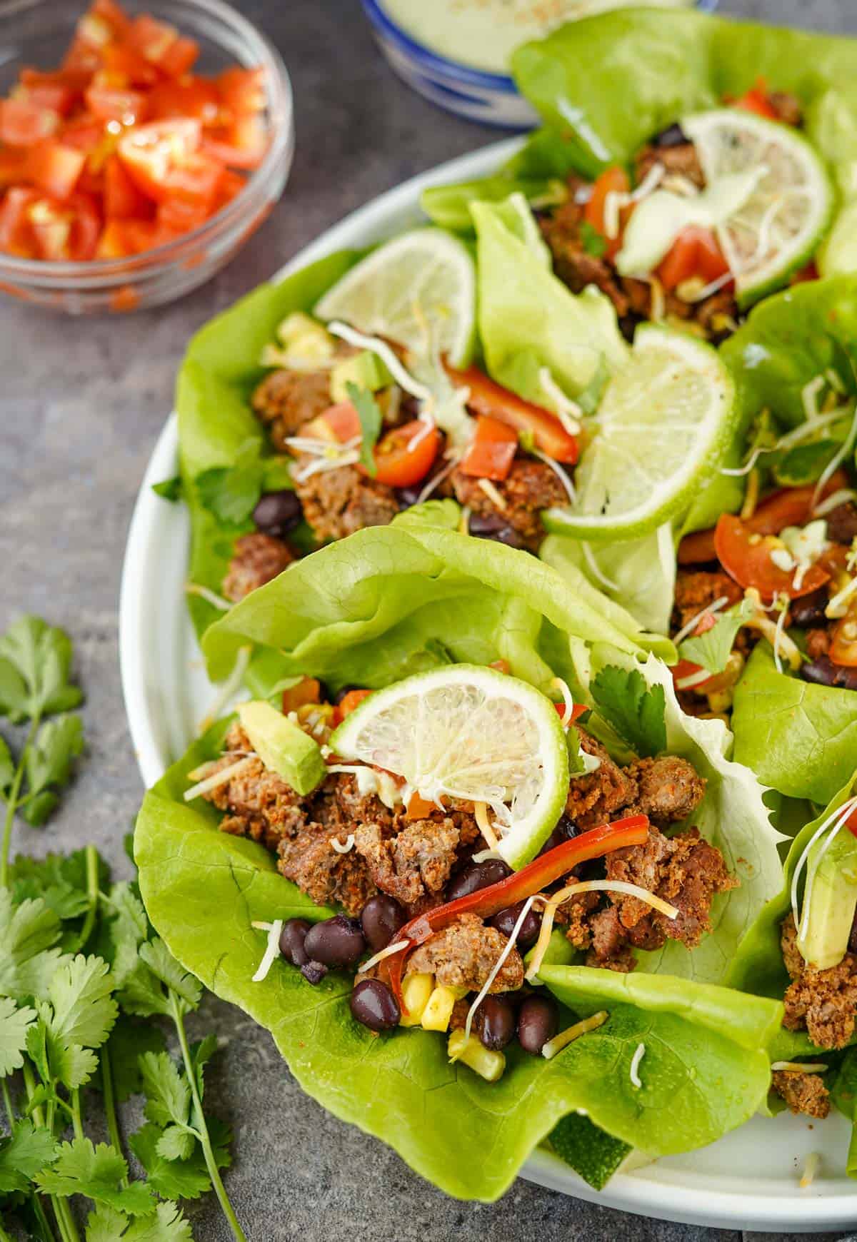 A plate filled with Taco Lettuce Wraps filled with smoked ground beef, black beans, cheese, and avocados
