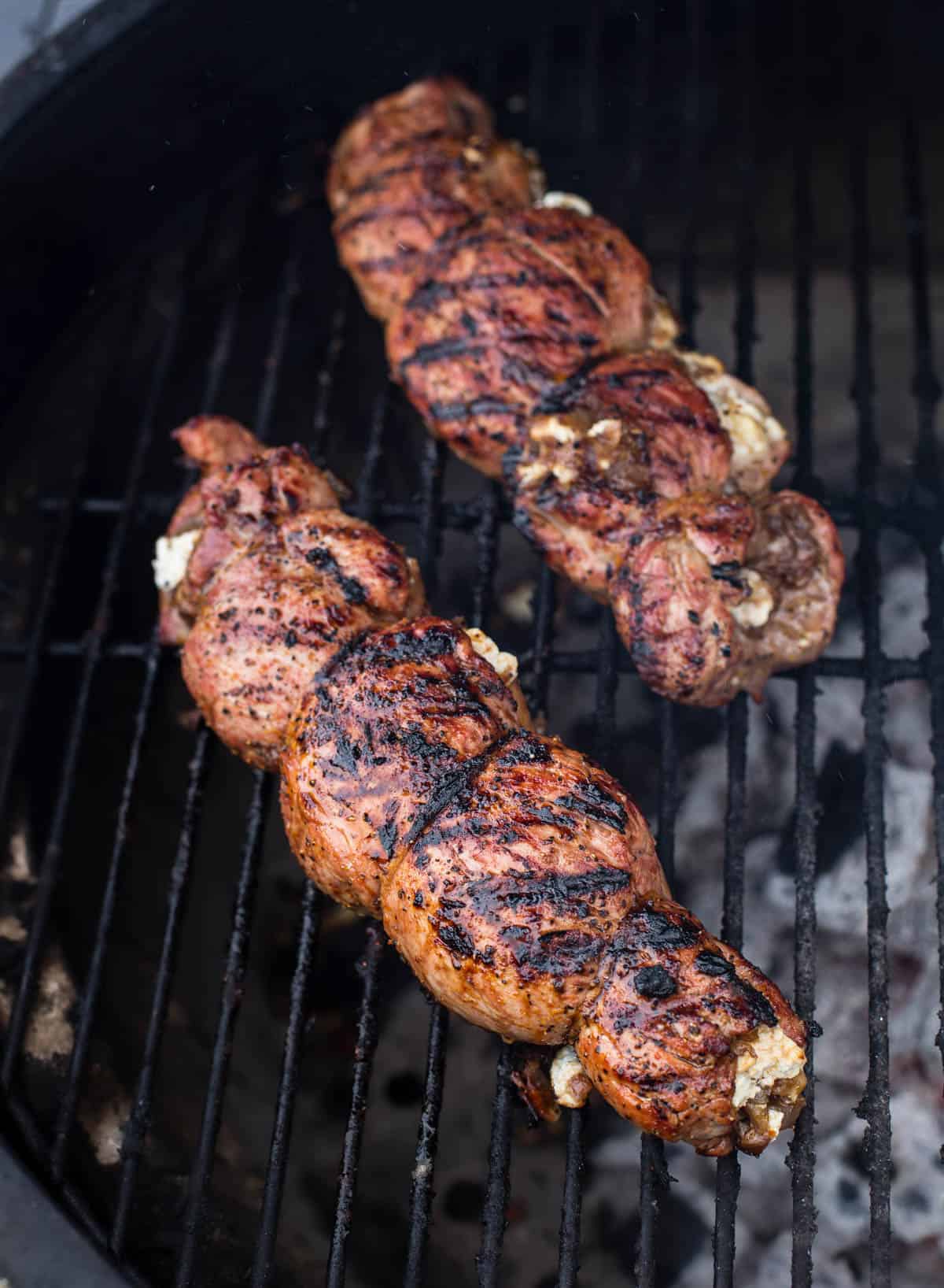 Two Stuffed Pork Tenderloins cooking on the grill