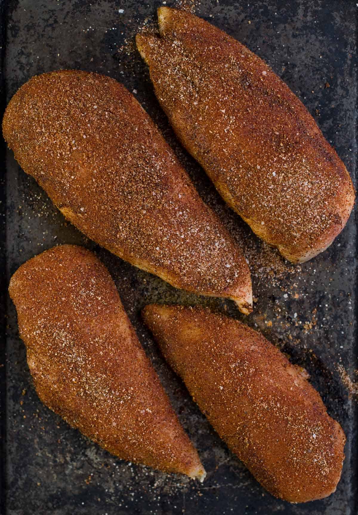 Raw boneless skinless chicken breasts coated with a dry seasoning