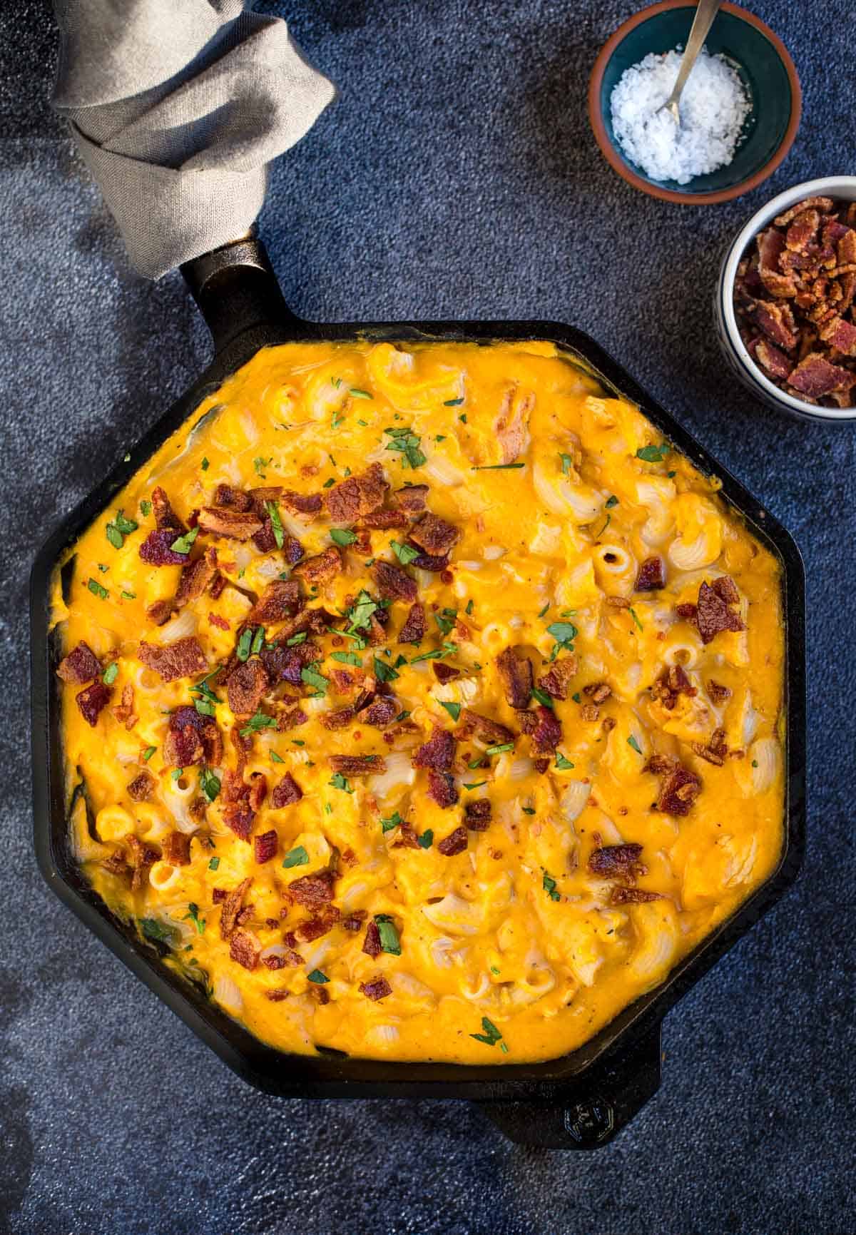 Smoked Butternut Squash Mac and Cheese in a cast iron pan topped with bacon
