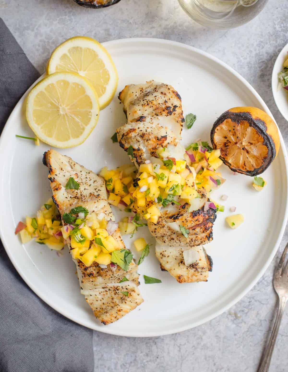 Grilled Halibut on a white plate topped with mango salsa