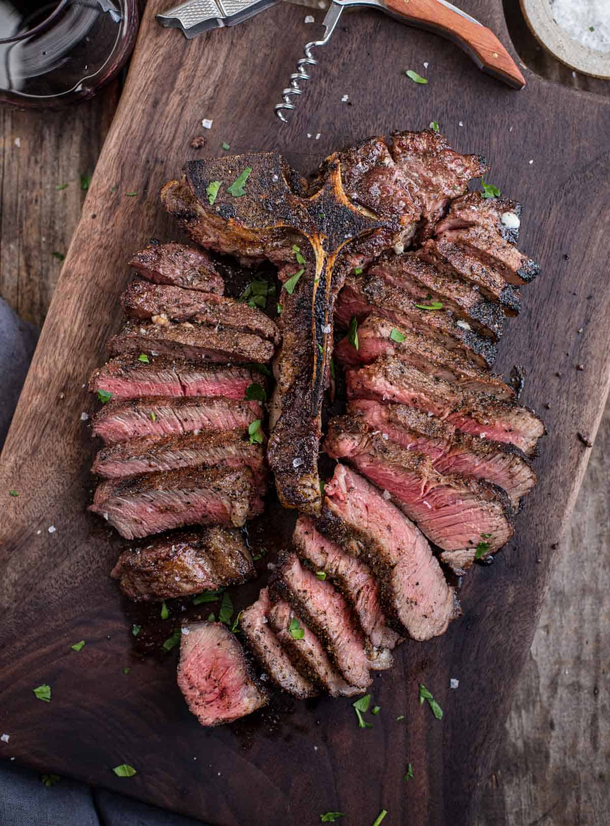 A Grilled Porterhouse Steak on a cutting board next to a glass of wine