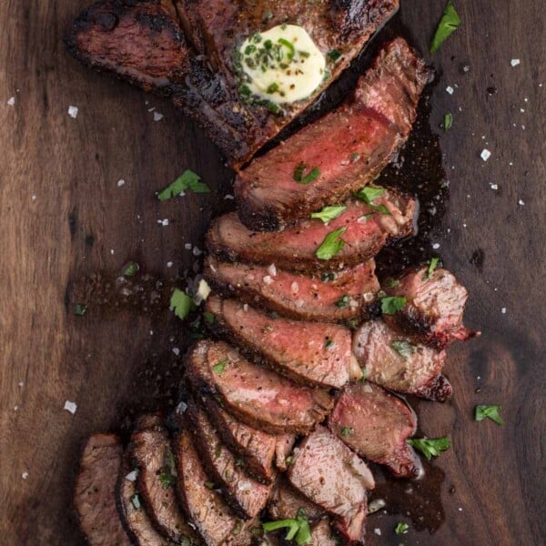 Grilled Sirloin Steak slices on a cutting board topped with herbed compound butter