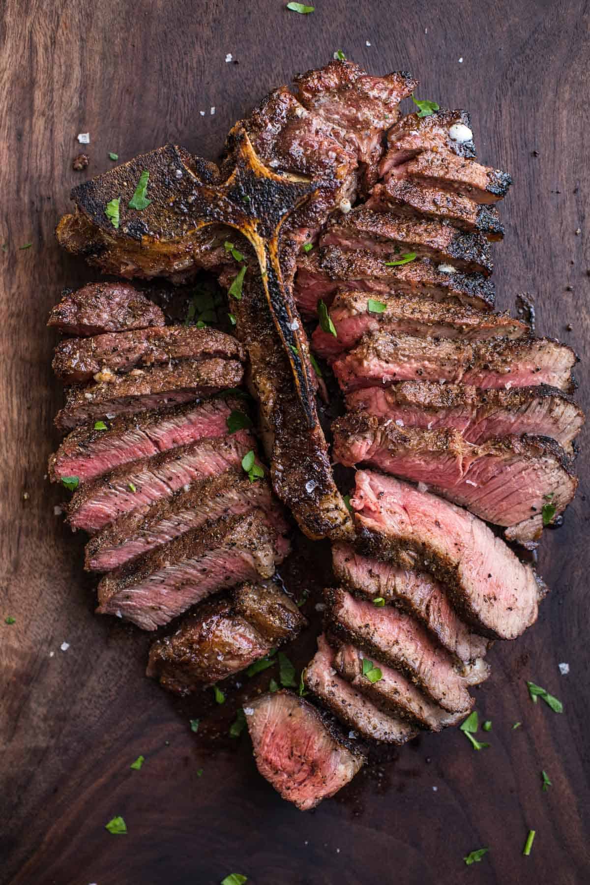 A Grilled Porterhouse Steak, sliced, on a wood cutting board