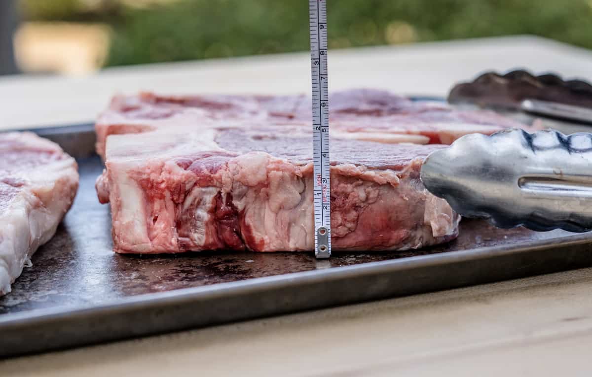 A raw steak side view with a ruler showing 1 1/2 inches thick