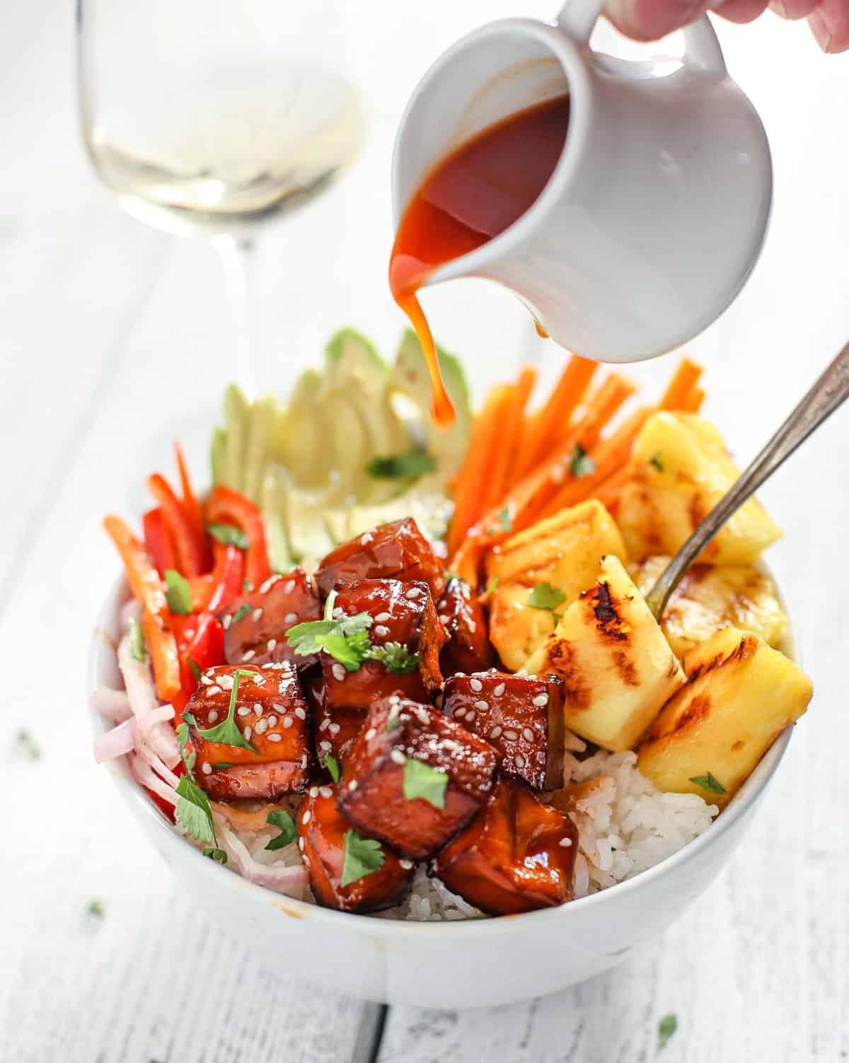 Smoked BBQ Tofu bowls with BBQ sauce being poured over the top