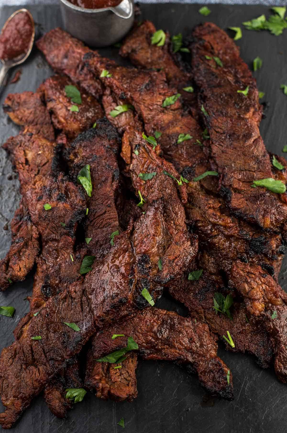 Slices of grilled marinated Flanken steak on a serving platter