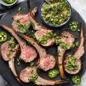 Grilled Lamb lollipops with Jalapeño chimichurri on a serving platter.