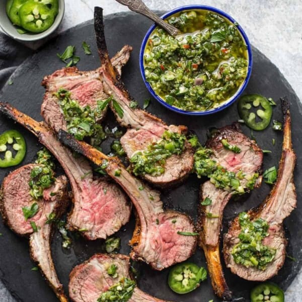 Grilled lamb rack cut into individual steaks with chimichurri sauce.