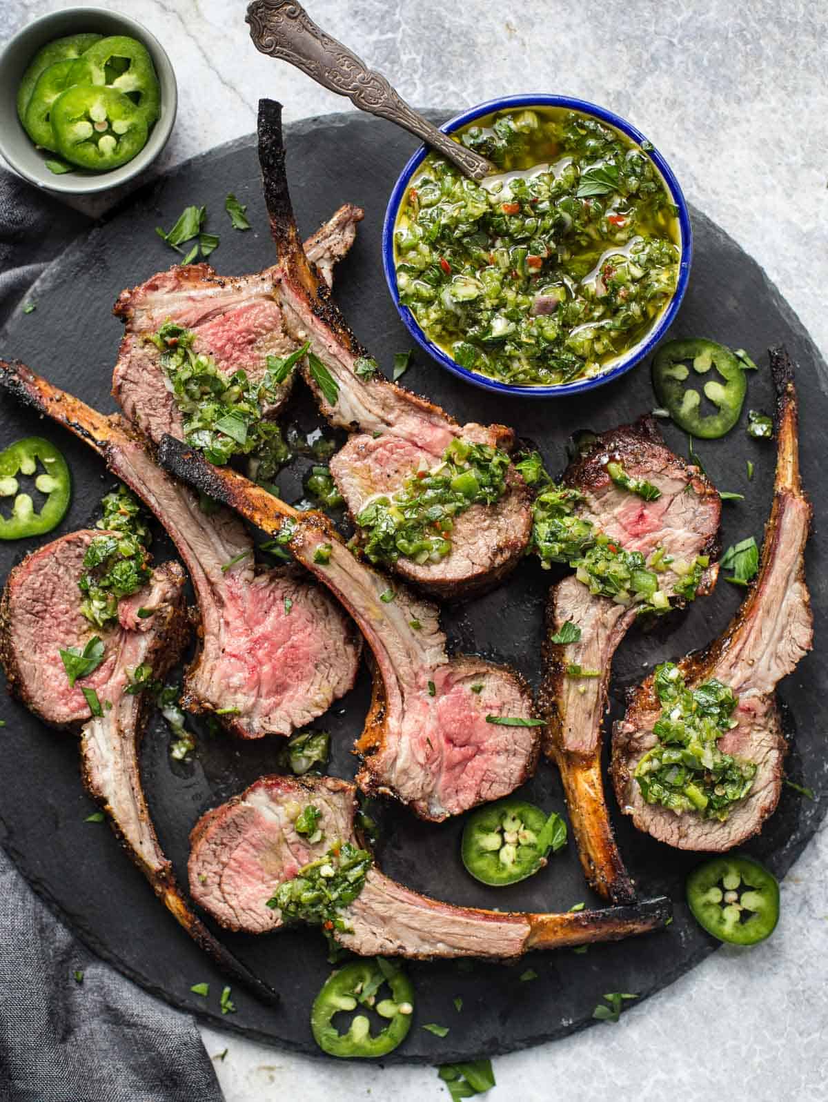 Grilled rack of lamb Lamb lollipops with Jalapeño chimichurri on a serving platter.