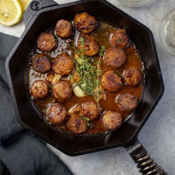 Grilled Scallops in a white wine pan sauce in cast iron pan.