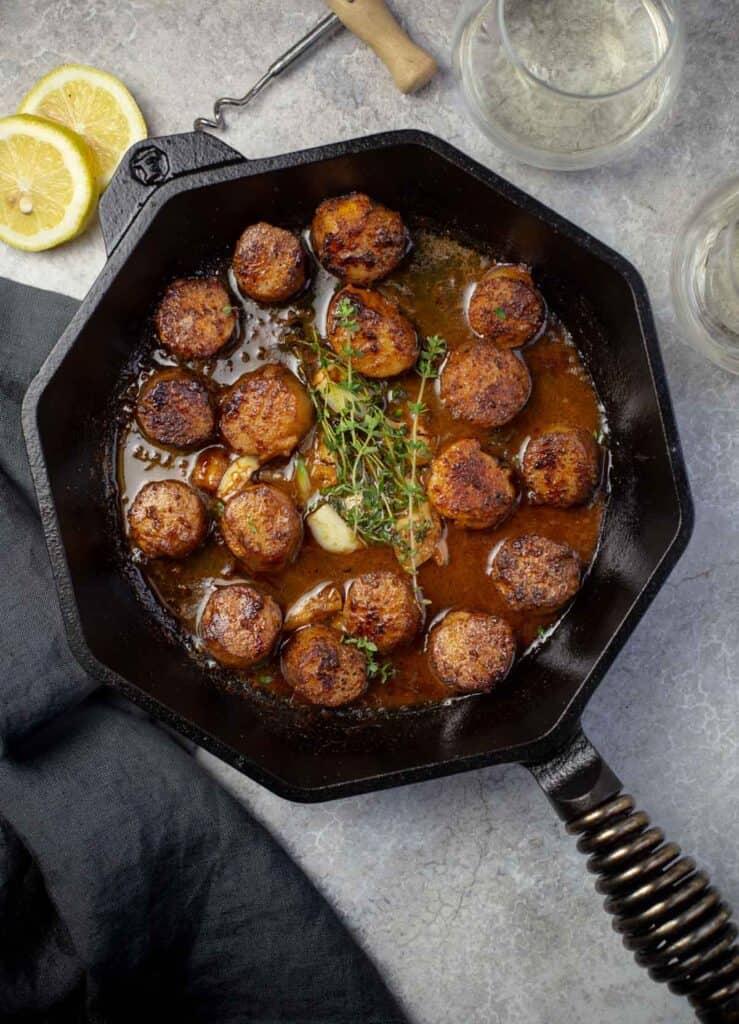 Grilled Scallops in a white wine pan sauce in cast iron pan.