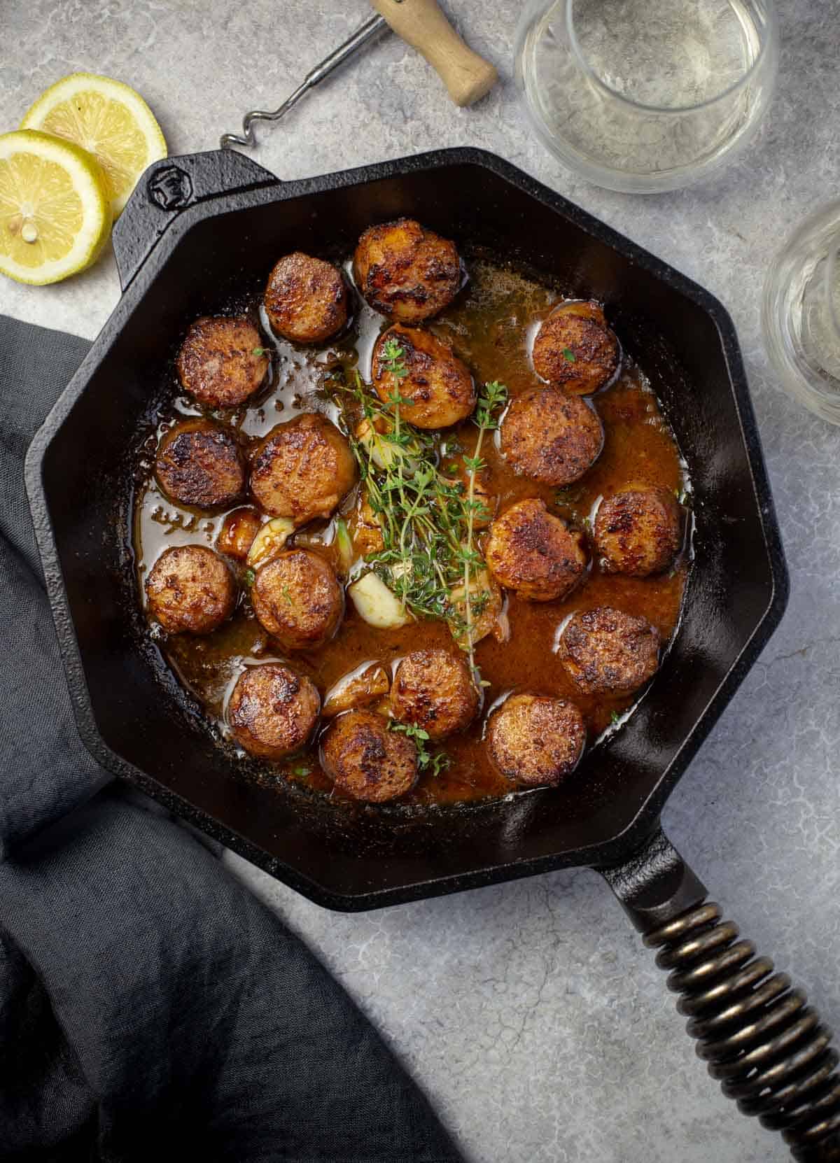 Grilled scallops in a cast iron pan with a white wine butter herb sauce