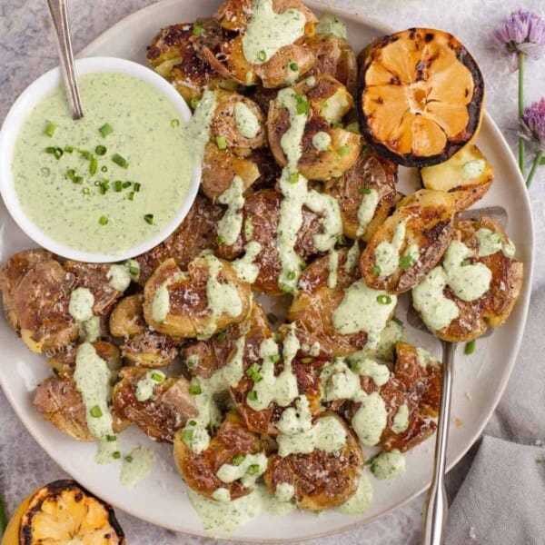 Grilled smashed potatoes with tarragon dipping sauce drizzled over the top.