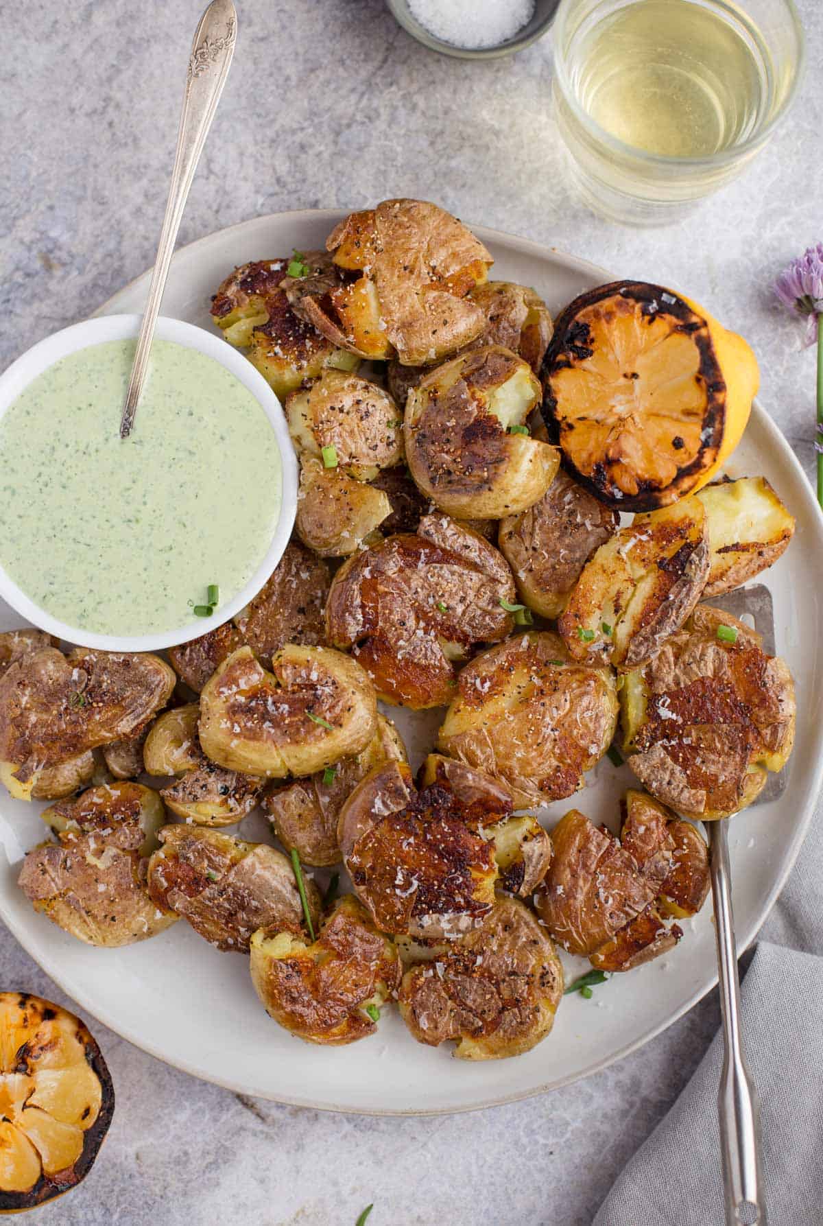 Grilled Smashed Potatoes with a tarragon cream sauce on a white plate