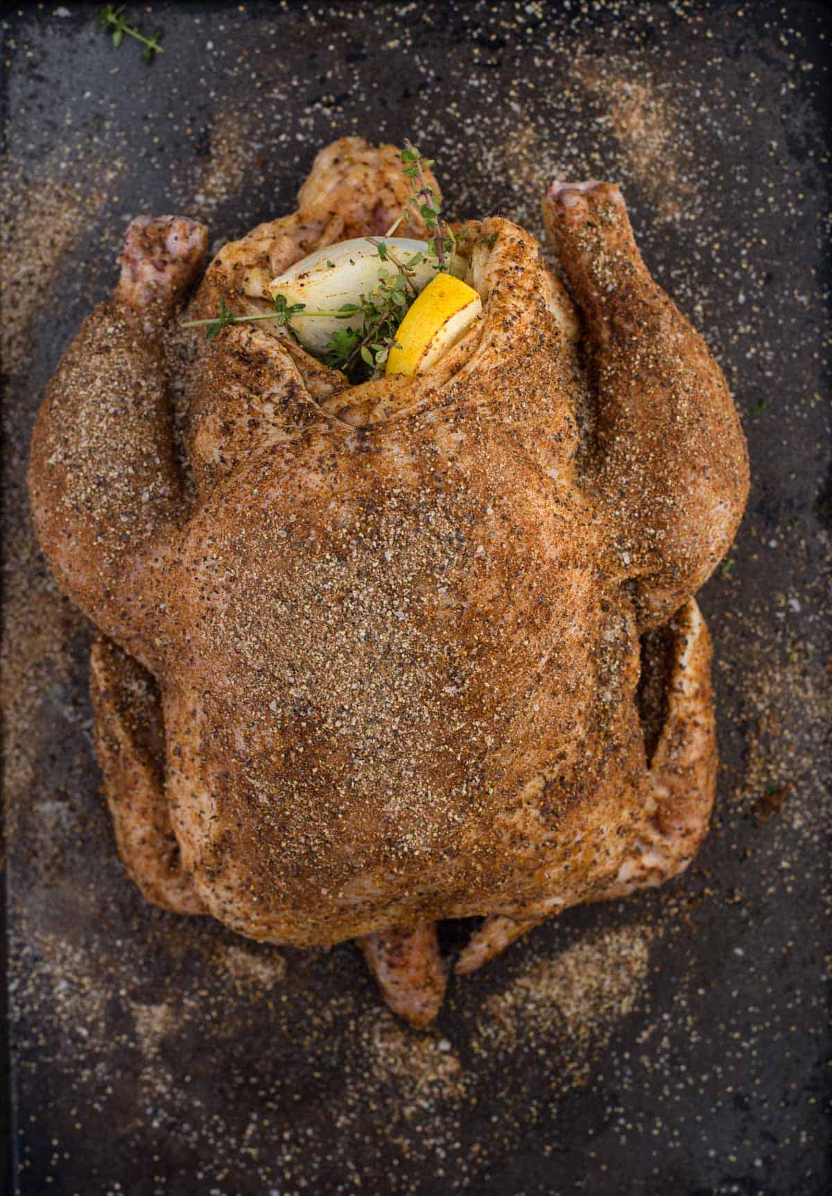 A whole chicken coated in poultry rub and stuffed with lemon, herbs, garlic, and onion. 