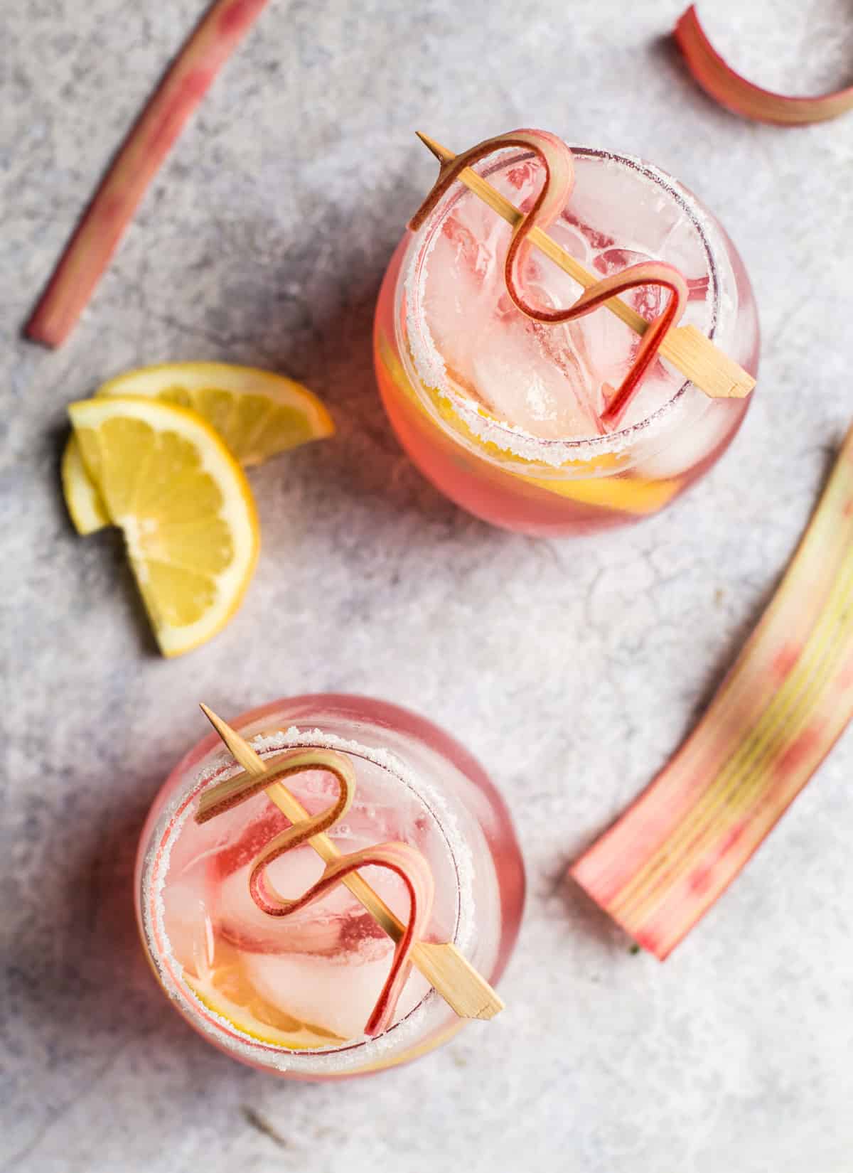 Top down view of two cocktails with rhubarb simple syrup and lemon 