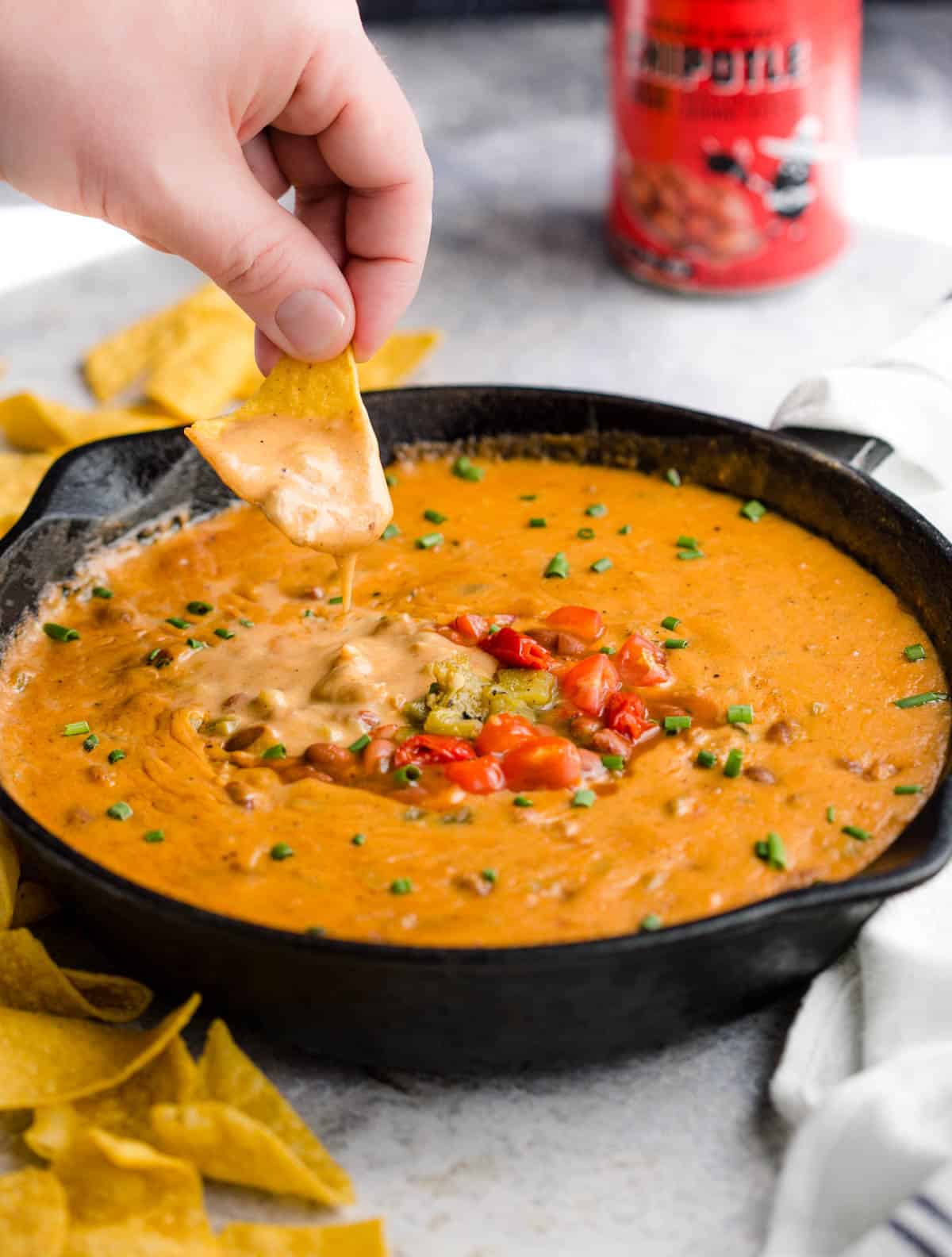 Dipping a chip into sausage queso bean dip. 