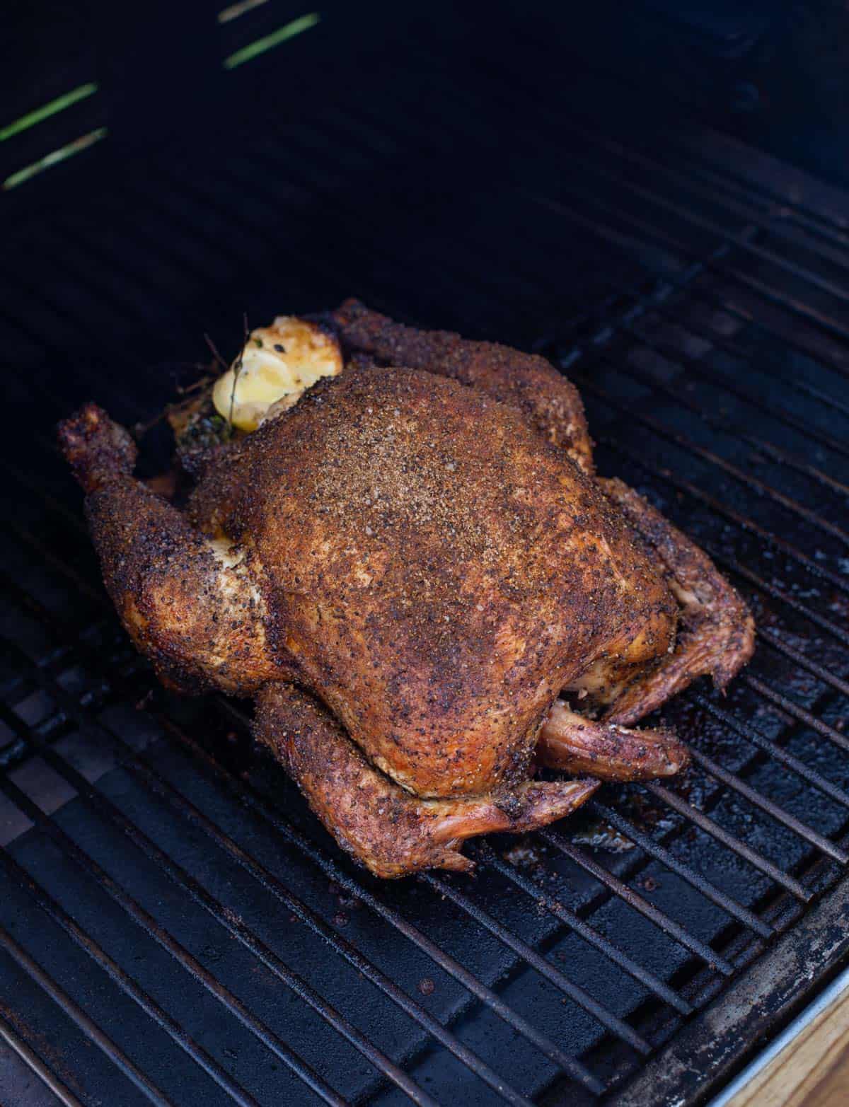 A whole chicken cooking on a pellet grill