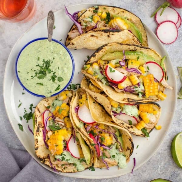 Corn and chicken tacos on a platter with tarragon sauce.