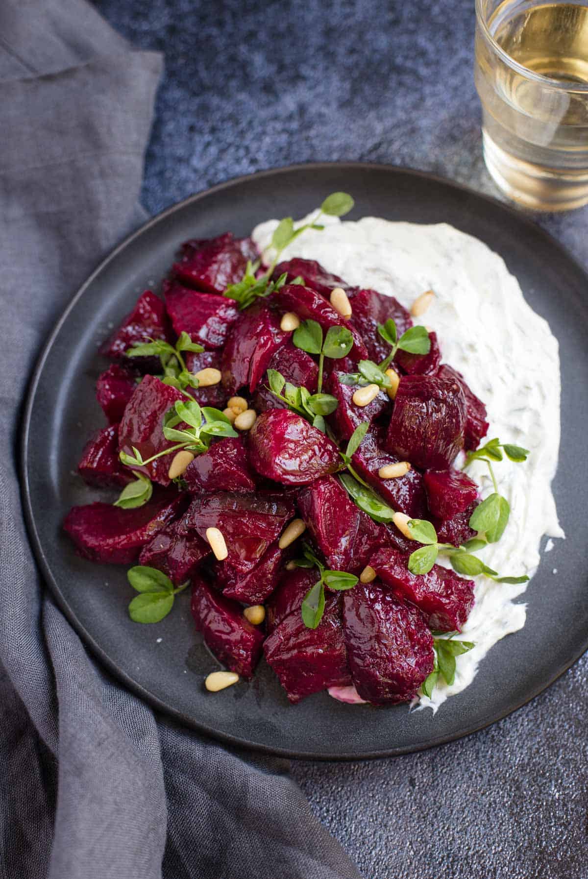Smoked Beets with Goat Cheese Ranch on a plate with a glass of white wine