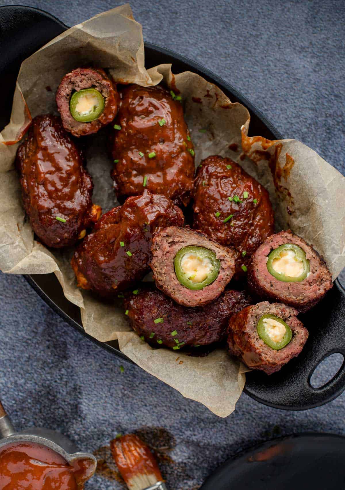 Smoked Armadillo Eggs in a pan with sauce.