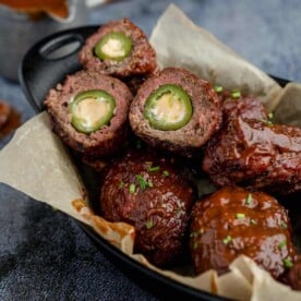 beef Armadillo Eggs in a cast iron pan with sauce.