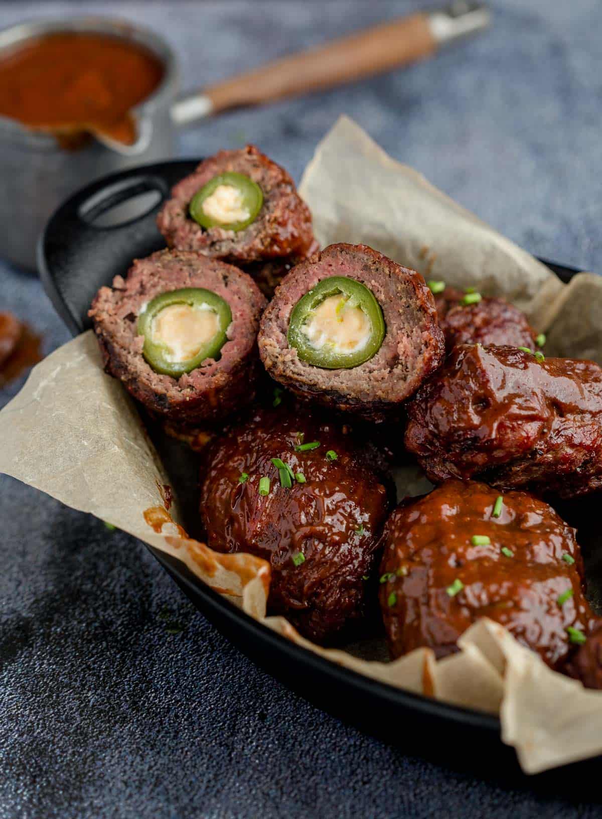 Beef Armadillo Eggs in a cast iron pan with a wine bbq sauce.