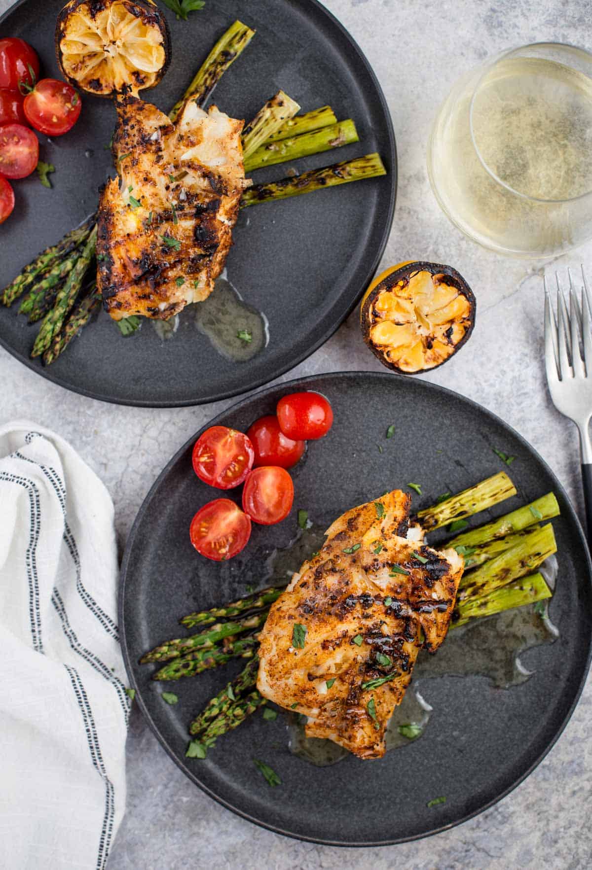 Two plates with grilled cod and a glass of white wine 