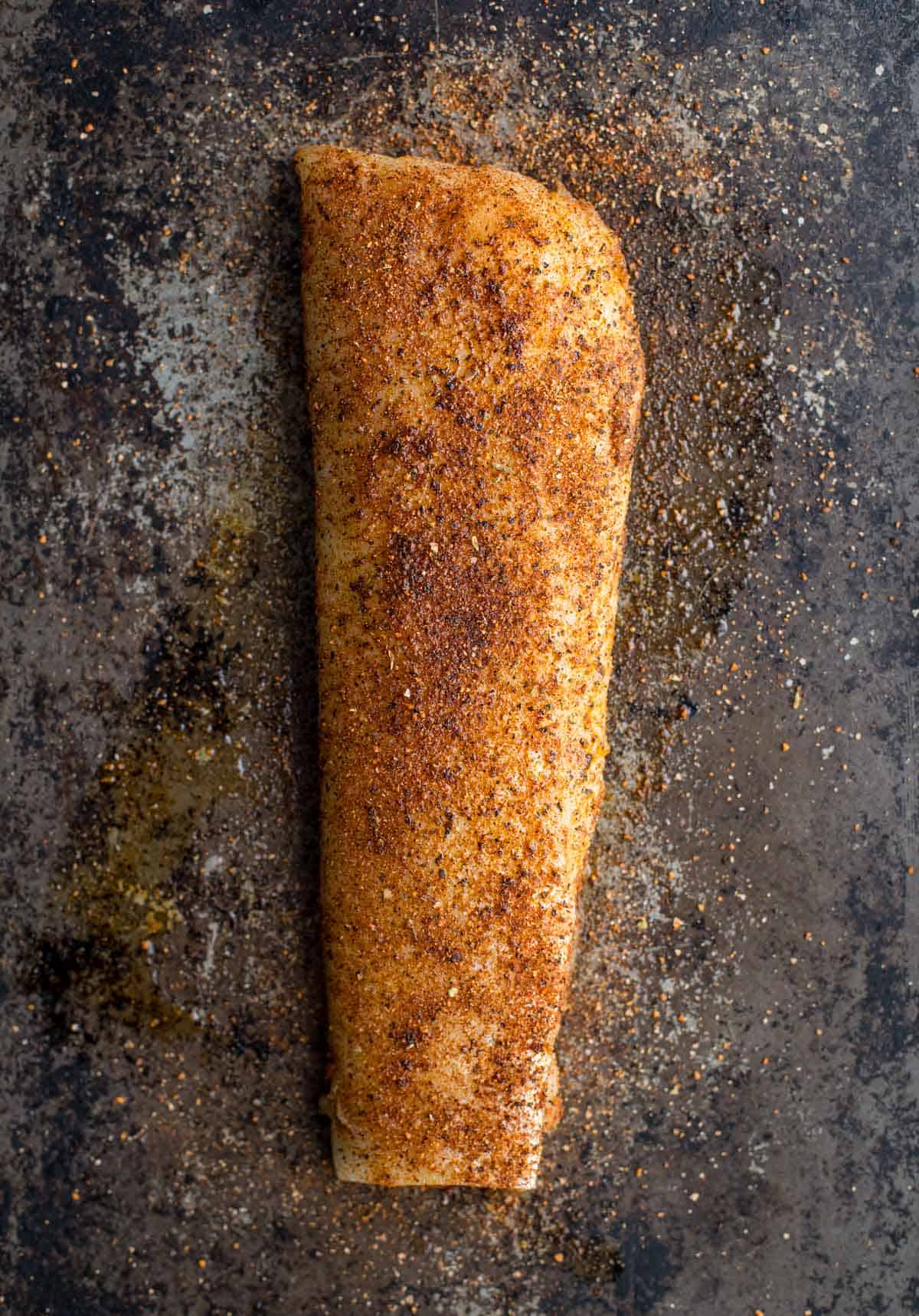 A filet of raw cod coated with Vindulge seafood seasoning