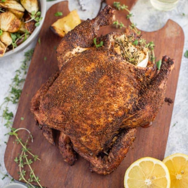 smoked chicken on a cutting board with potatoes.