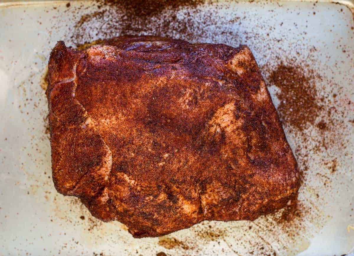A raw pork butt coated with the best dry rub for pork 