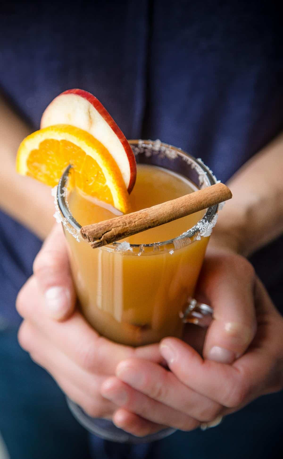 Holding a glass of warm spiked apple cider 