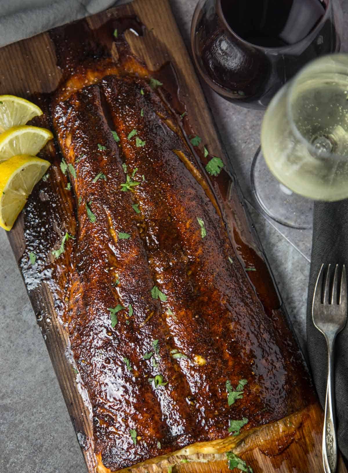 A Maple Chipotle Cedar Plank Salmon on a cutting board with a glass of wine